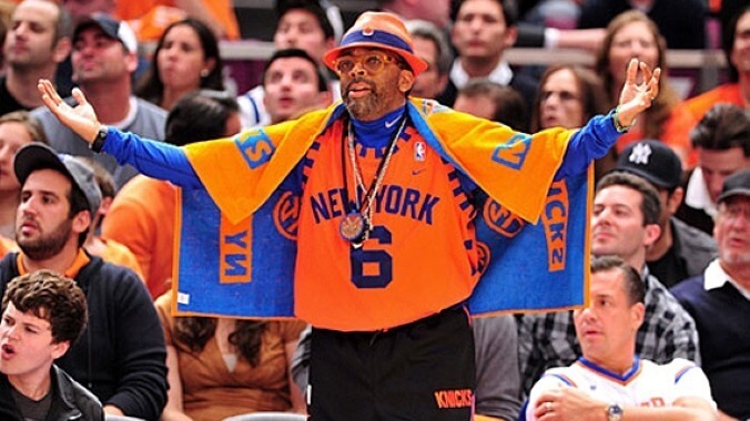 Spike Lee, dressed in New York Knicks gear, standing courtside with his arms out looking upset
